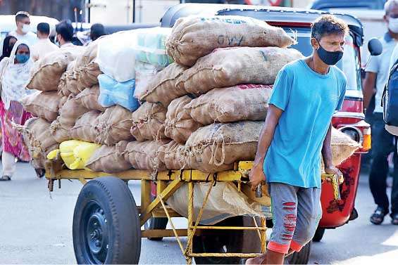 A worker pulling a hand-cart laden with goods