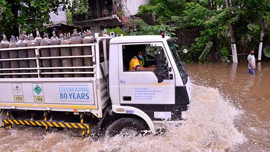 Lorry carrying oxygen cylinders wades through floodwater