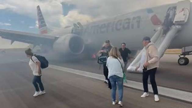 Passengers exit plane via emergency slide after aborted takeoff