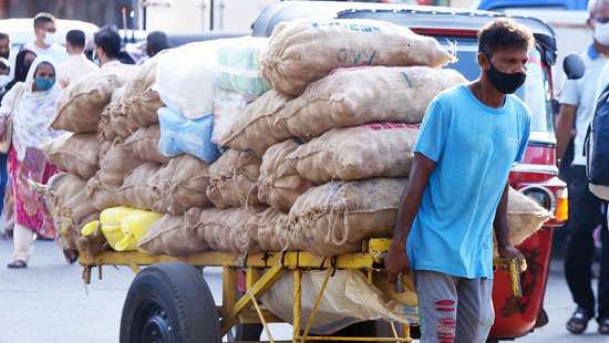 A worker pulling a hand-cart laden with goods