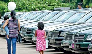 A woman and her two children walk past a line of Mercedes-Benz cars